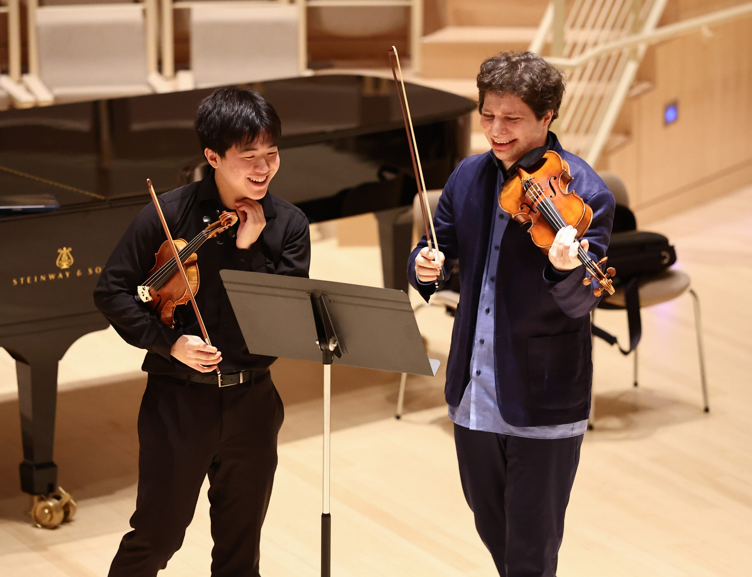 Two students playing string instruments during a rehearsal.